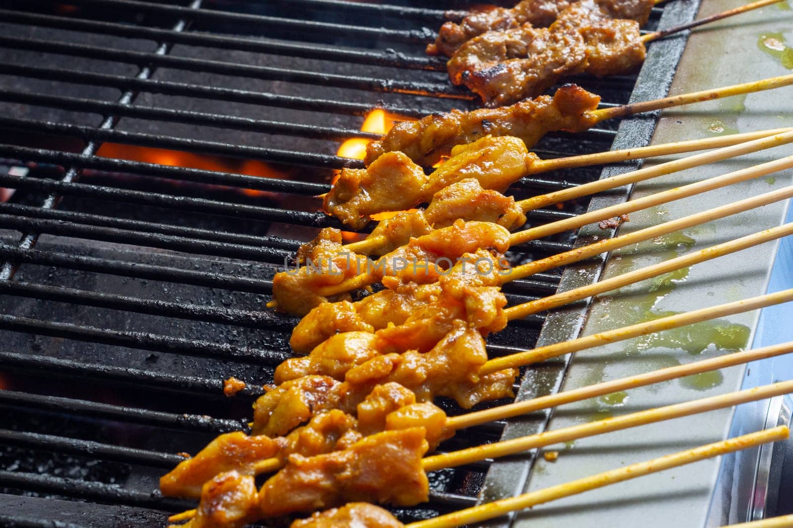 Asian cuisine, Malaysia chicken satay cooking on a hot charcoal grill. by JennMiranda