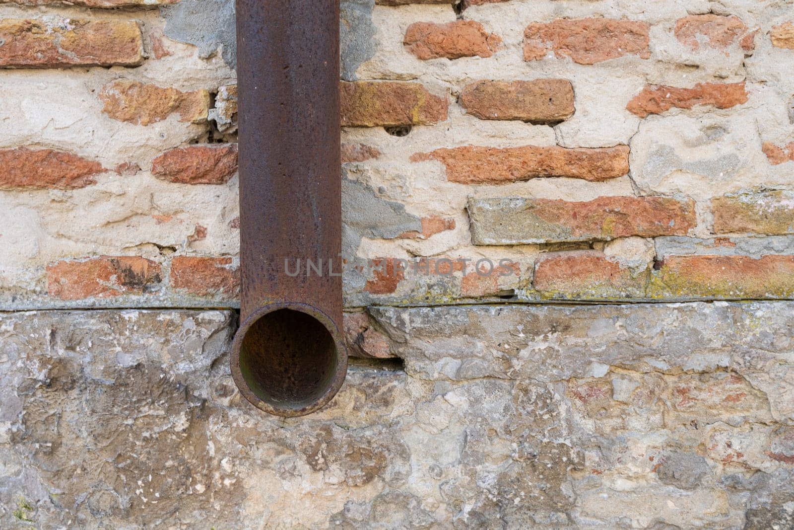 the old pipe of a gutter on a brick wall