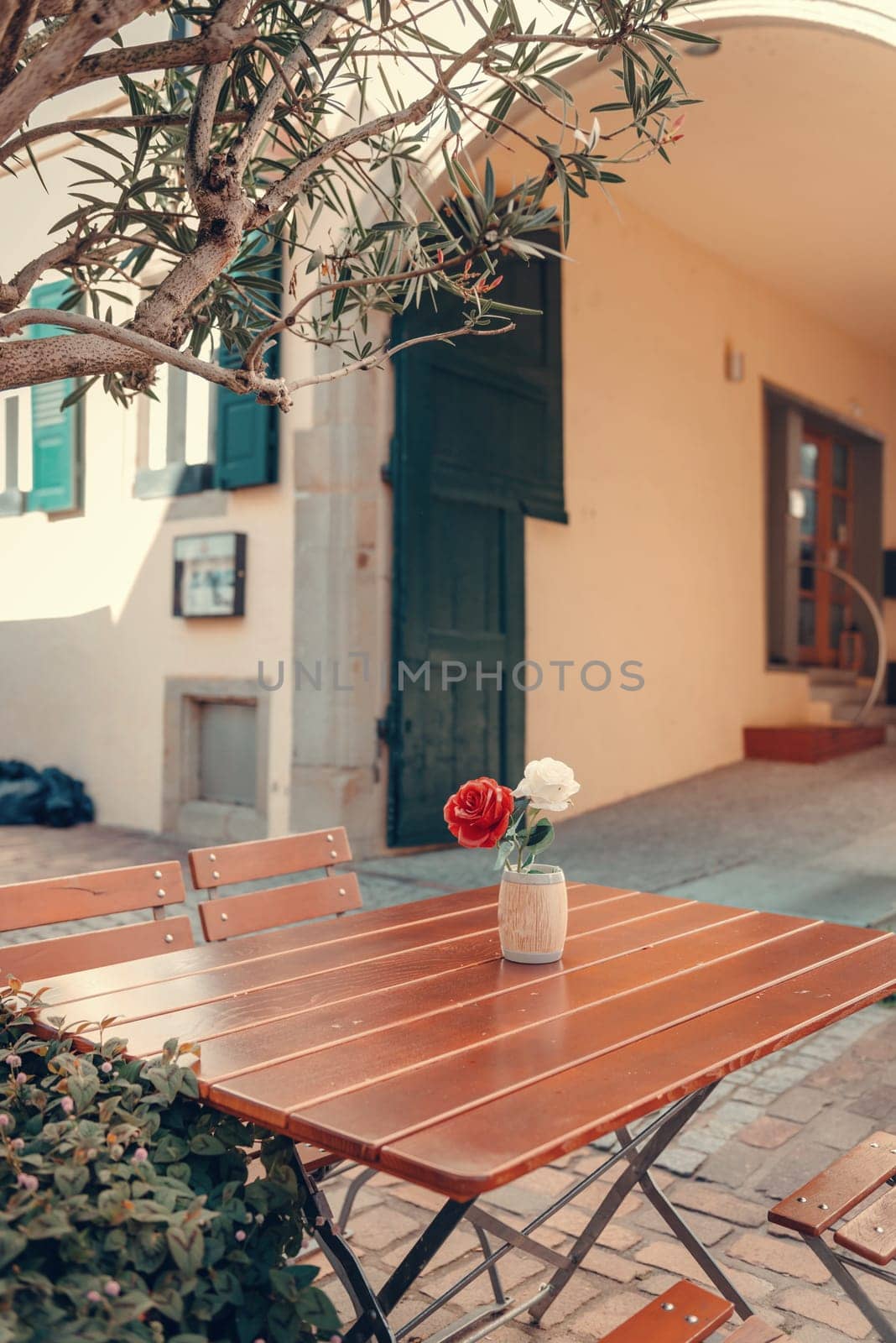 Empty cafe terrace with white table and chair. exterior of the cafe restaurant. interior Street cafe. Cozy street with flowers and French-style cafe table. Decor facade of coffeehouse with bike. Table on a summer terrace with cake and teapot. Garden table and chairs