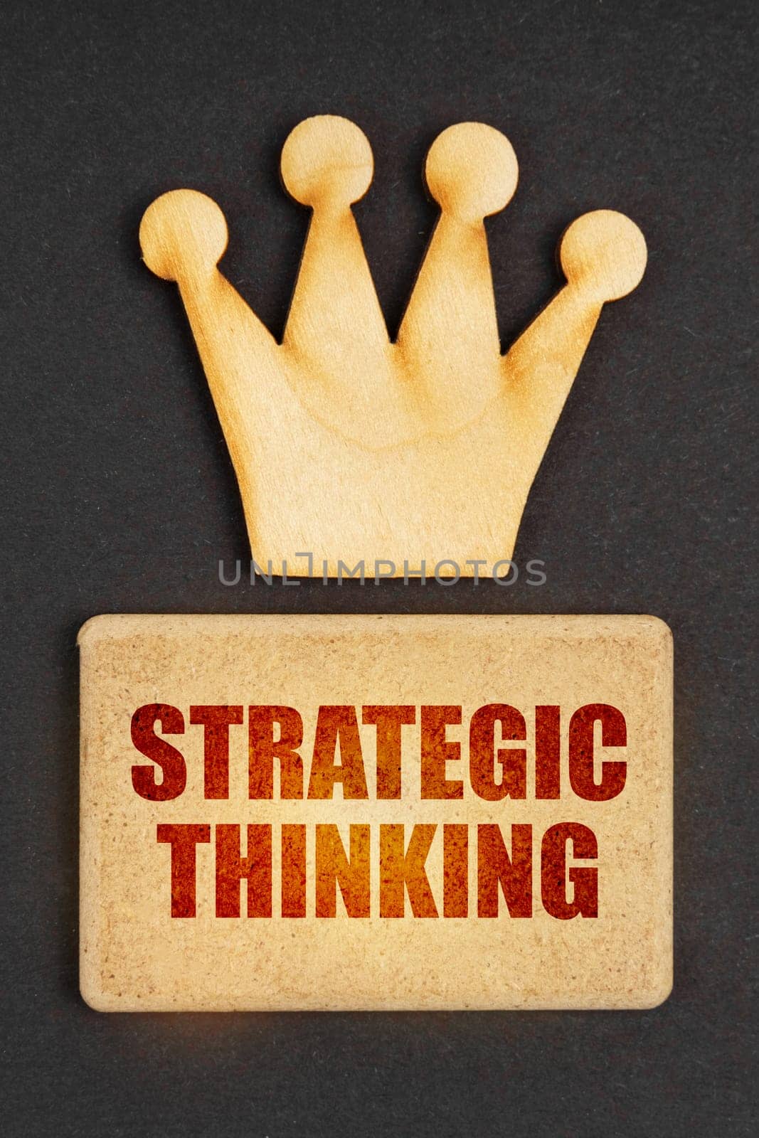 Business concept. On a black background there is a wooden crown of the leader and a sign with the inscription - Strategic Thinking