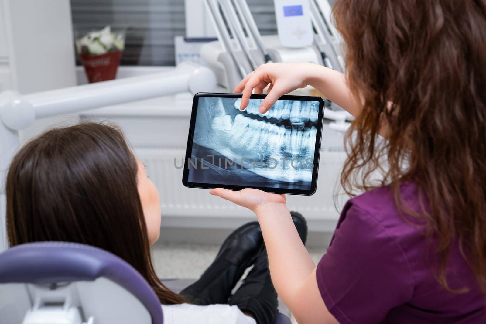 A female dentist discusses treatment options with the patient while displaying the X ray