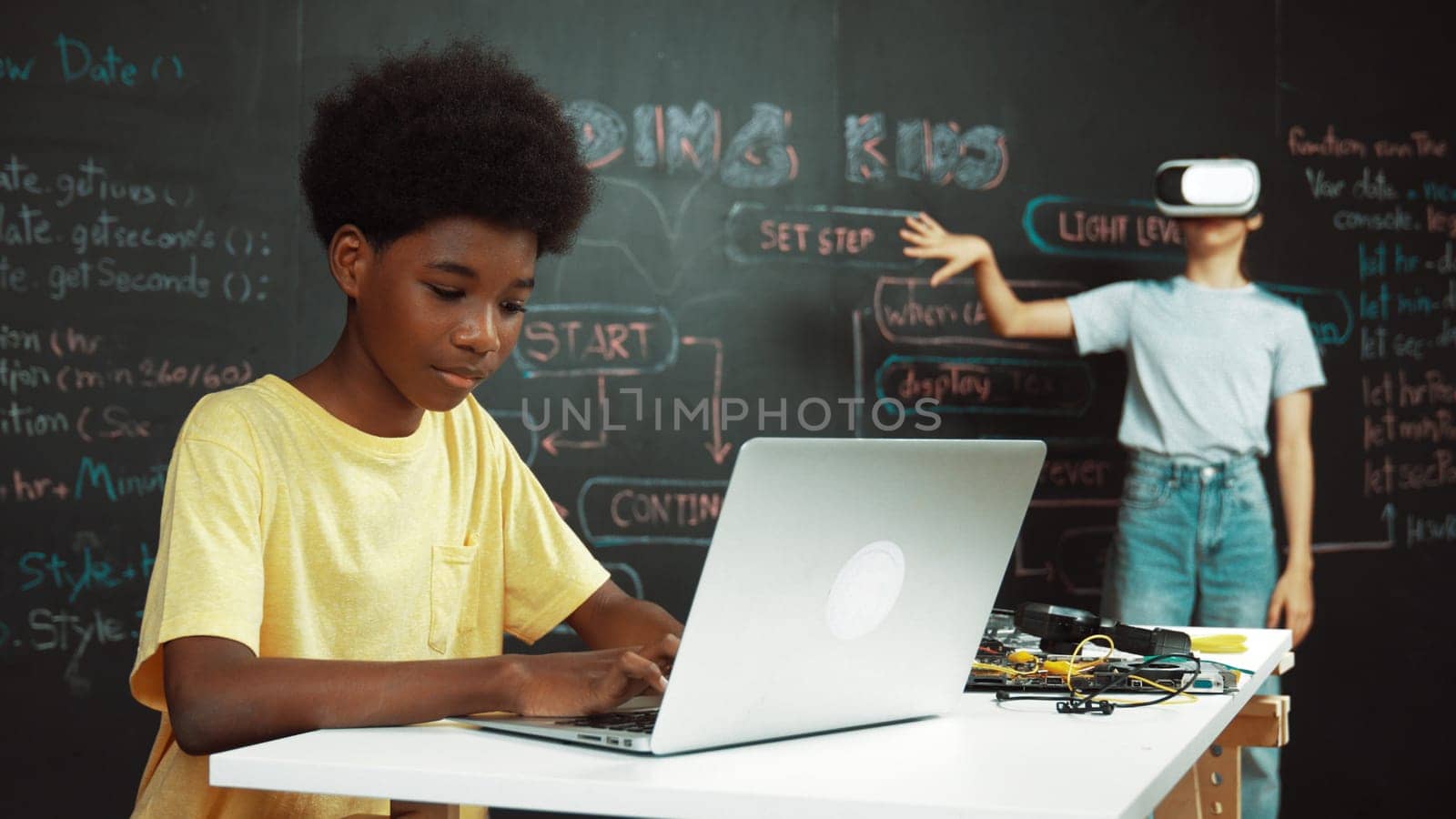 Smart african student programing and coding innovative system while caucasian girl enter in metaverse or virtual world by using VR or head set at blackboard in STEM technology classroom. Edification.