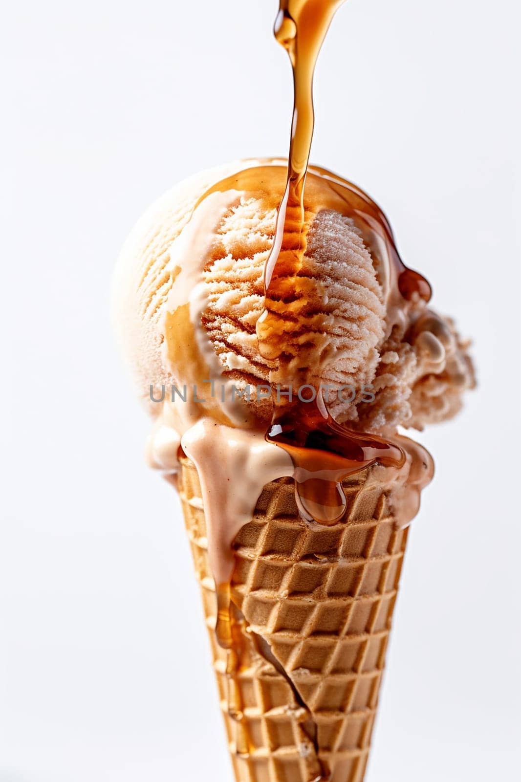 A scoop of ice cream on a cone with caramel drizzling over it.