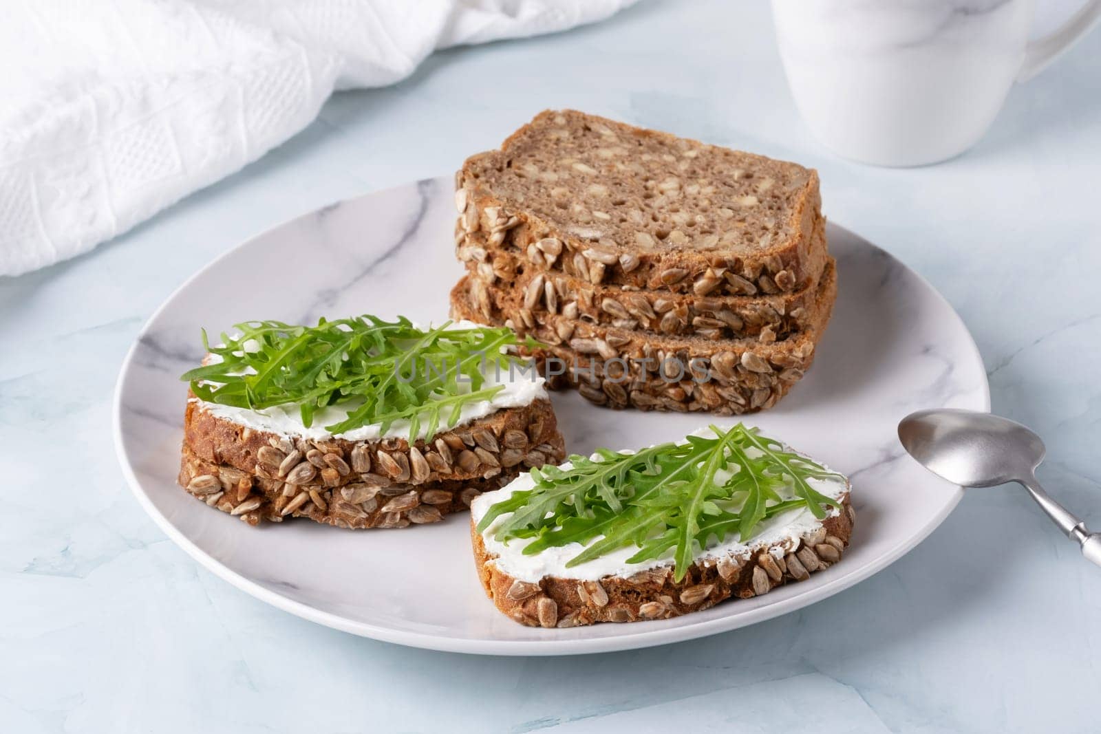 Sandwiches with curd cheese and arugula. Rye bread with seeds.