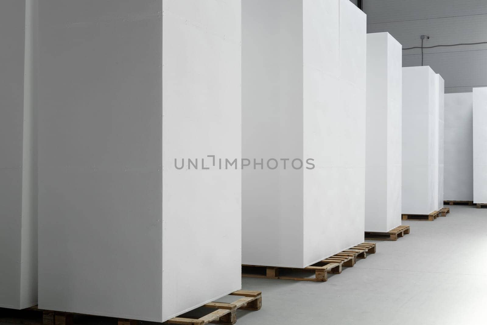A large blocks of Styrofoam are stacked in a warehouse. Industrial production of polystyrene foam insulation panels or plates from expanded polystyrene. Building materials.