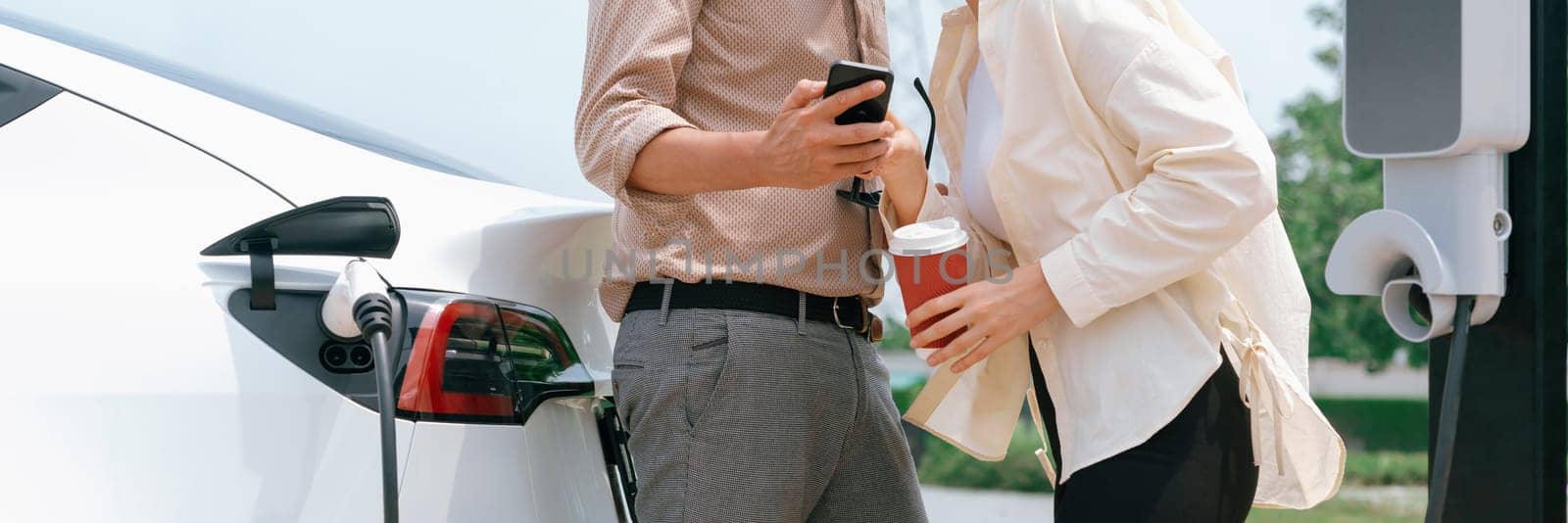 Young couple put EV charger to recharge electric car battery. Expedient by biancoblue