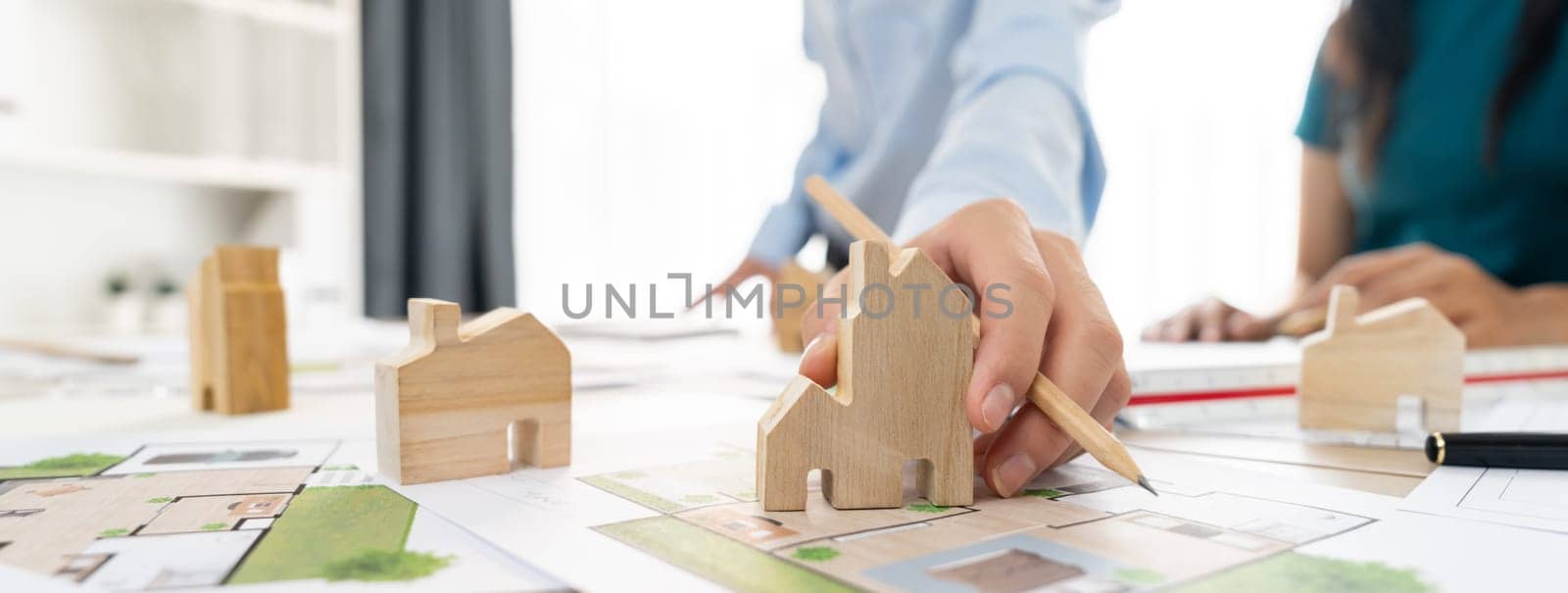 Professional architect engineer team discussion about architectural project on meeting table with wooden block and blueprint scatter around. Design and cooperate concept. Closeup. Delineation.