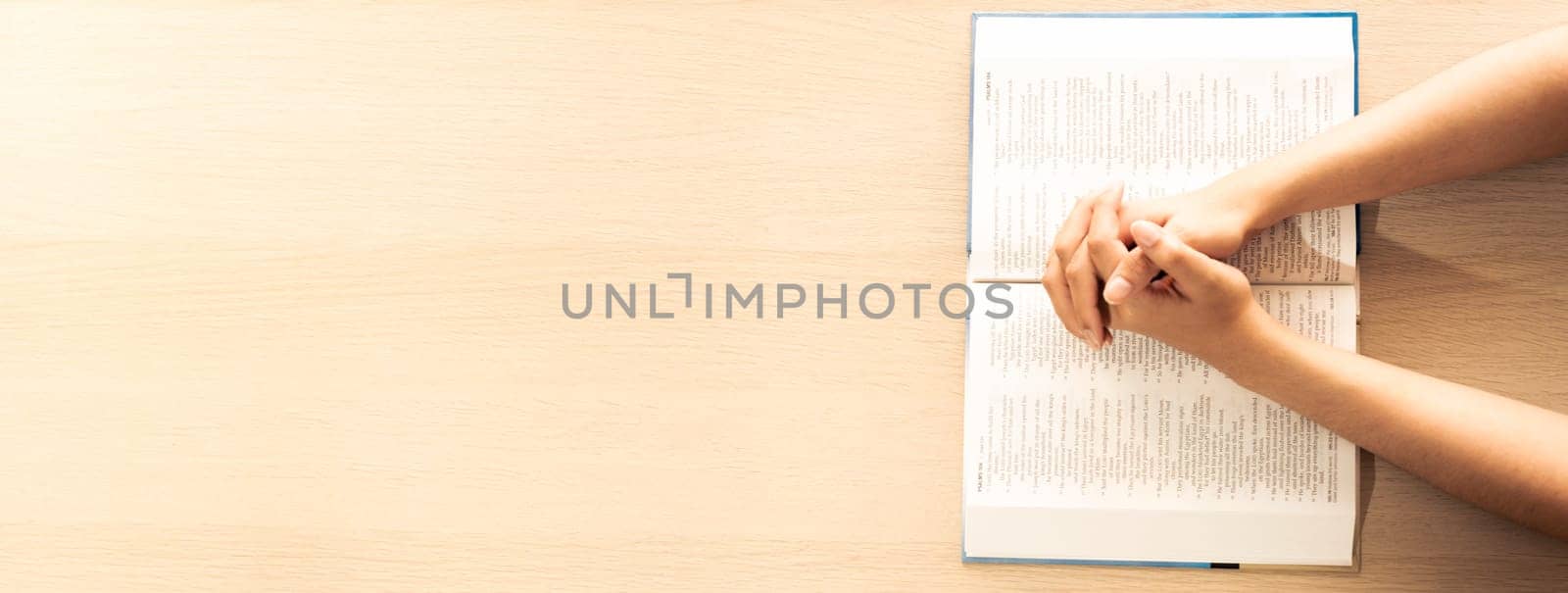 Female prayer folding hand on holy bible book on wooden church table. Concept of hope, religion, faith, christianity praying for love and god blessing. Warm and brown background.Top view. Burgeoning.