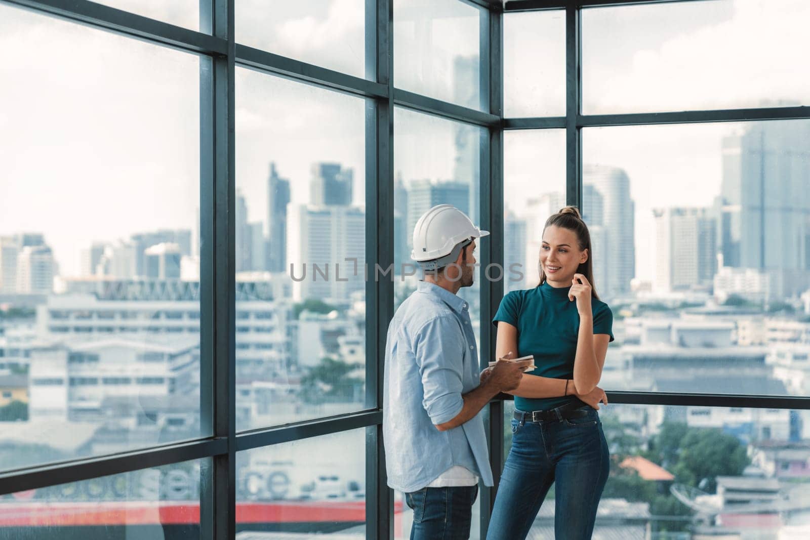 Professional smart architect engineer team discuss and solve building construction problems. Engineer taking a note while listening manager sharing idea about work surrounded by skyscraper. Tracery.