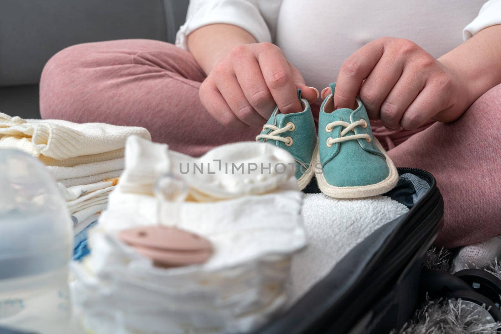 Mother holding baby shoes on belly. Maternity prenatal care and pregnancy concept