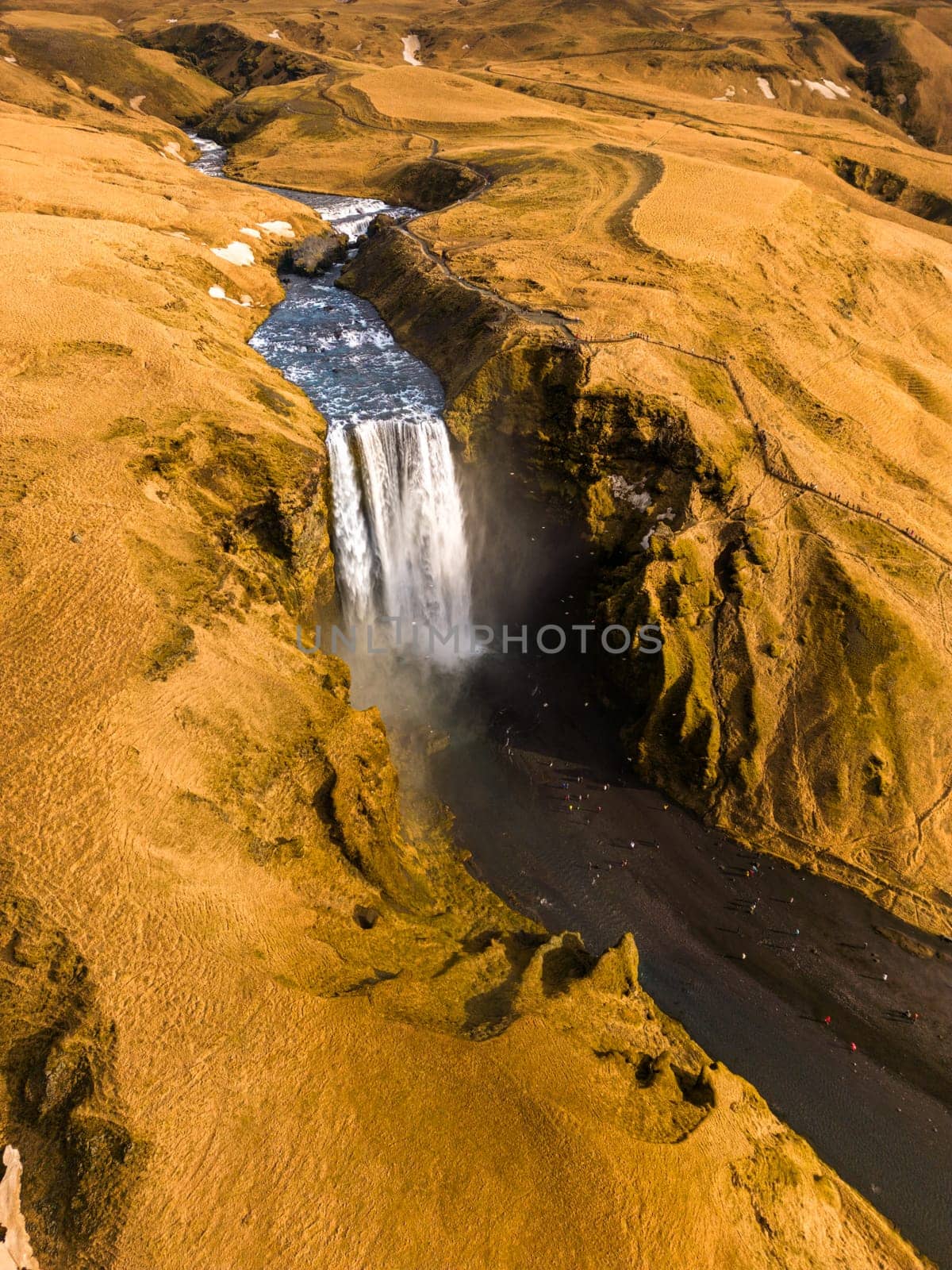 Drone shot of major waterfall in Iceland, with overflow of water falling down from magnificent brown stones. Beautiful scenery formed by amazing icelandic skgafoss cascade pouring over hills.