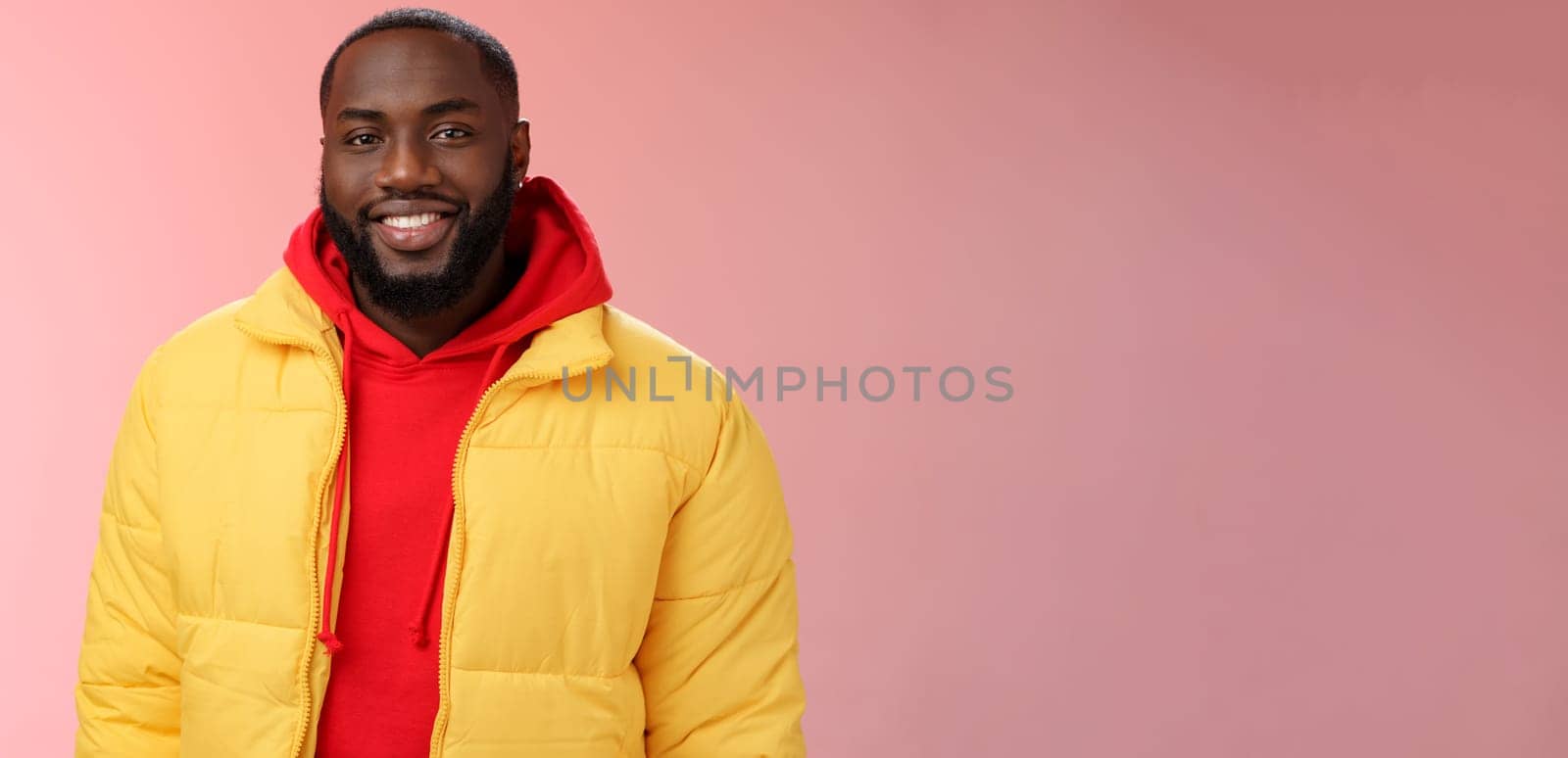 Waist-up happy charismatic good-looking bearded guy in yellow jacket red hoodie smiling joyfully white perfect smile talking have nice friendly conversation, standing pink background.