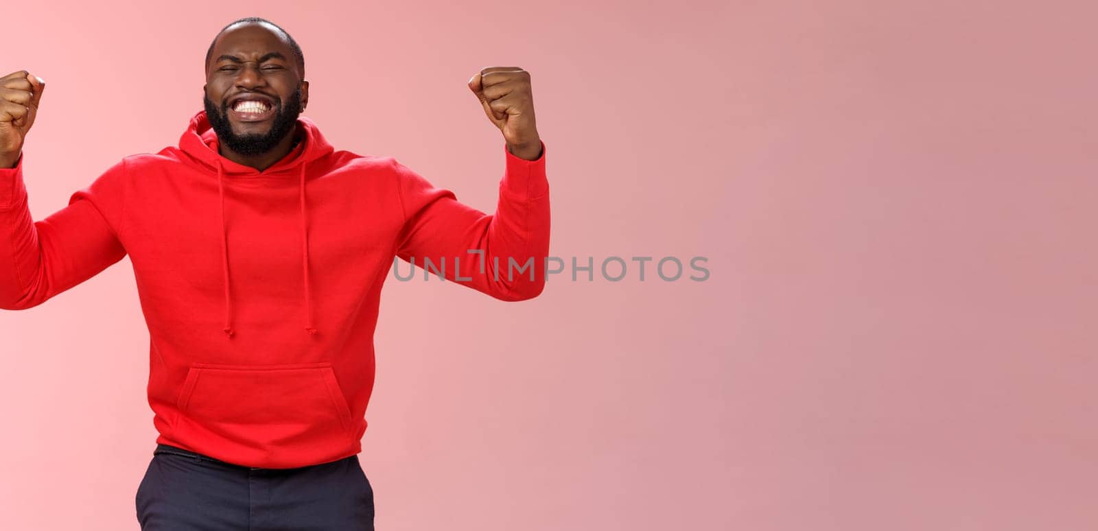 Happy thankful young african american bearded man thank god for son close eyes joyfully smiling clench fists celebrating triumphing dream come true accomplish goal, cheering victory.