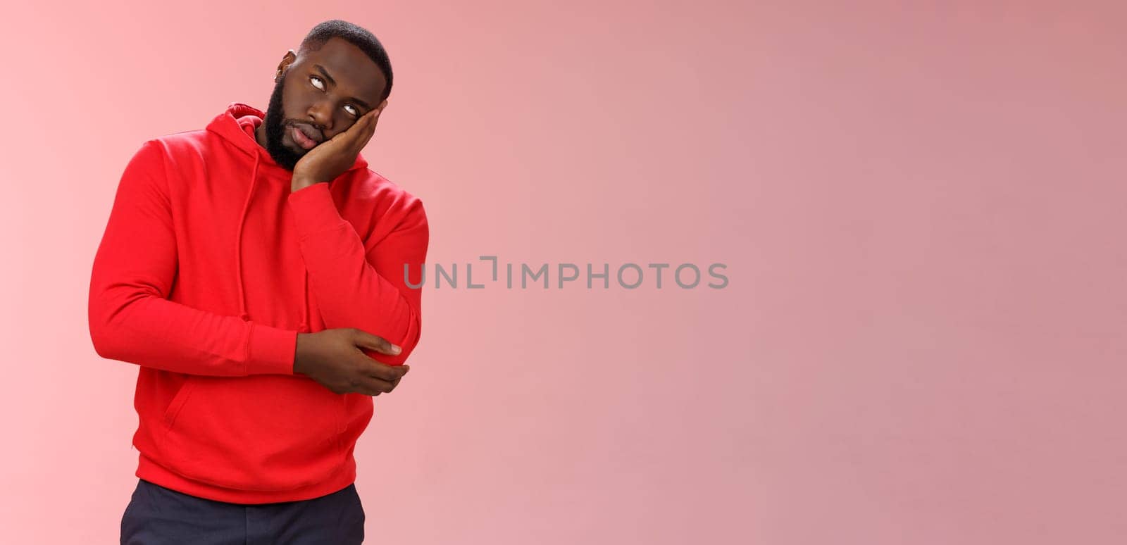 Annoyed bored funny attractive african american guy in red hoodie roll eyelids facepalm head lean hand, hear stupid uninteresting story dying boredom, standing careless rude pink background by Benzoix