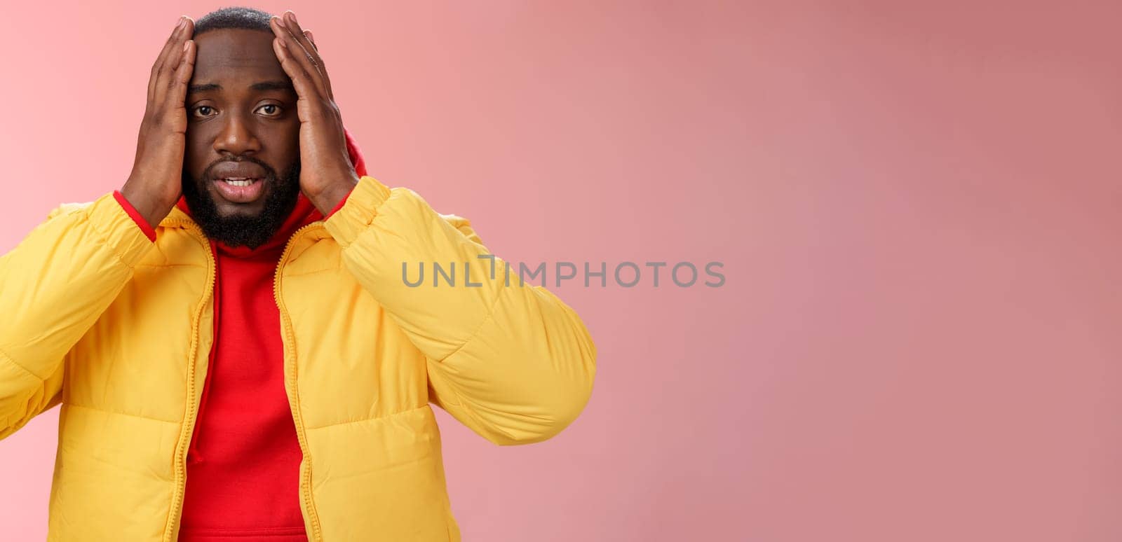 Shocked upset african-american bearded guy feel regret stunned hear terrible news hold hands head widen eyes stupor standing speechless troubled, look perplexed terribly sad, pink background.