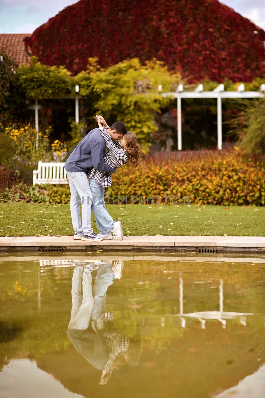 A couple in love hugs on the shore of a city pond in the European town. love story against the backdrop of autumn nature. romantic ambiance, couple goals, outdoor romance, seasonal charm, love in the city, autumnal vibes, European town, city pond, affectionate bonding, love story