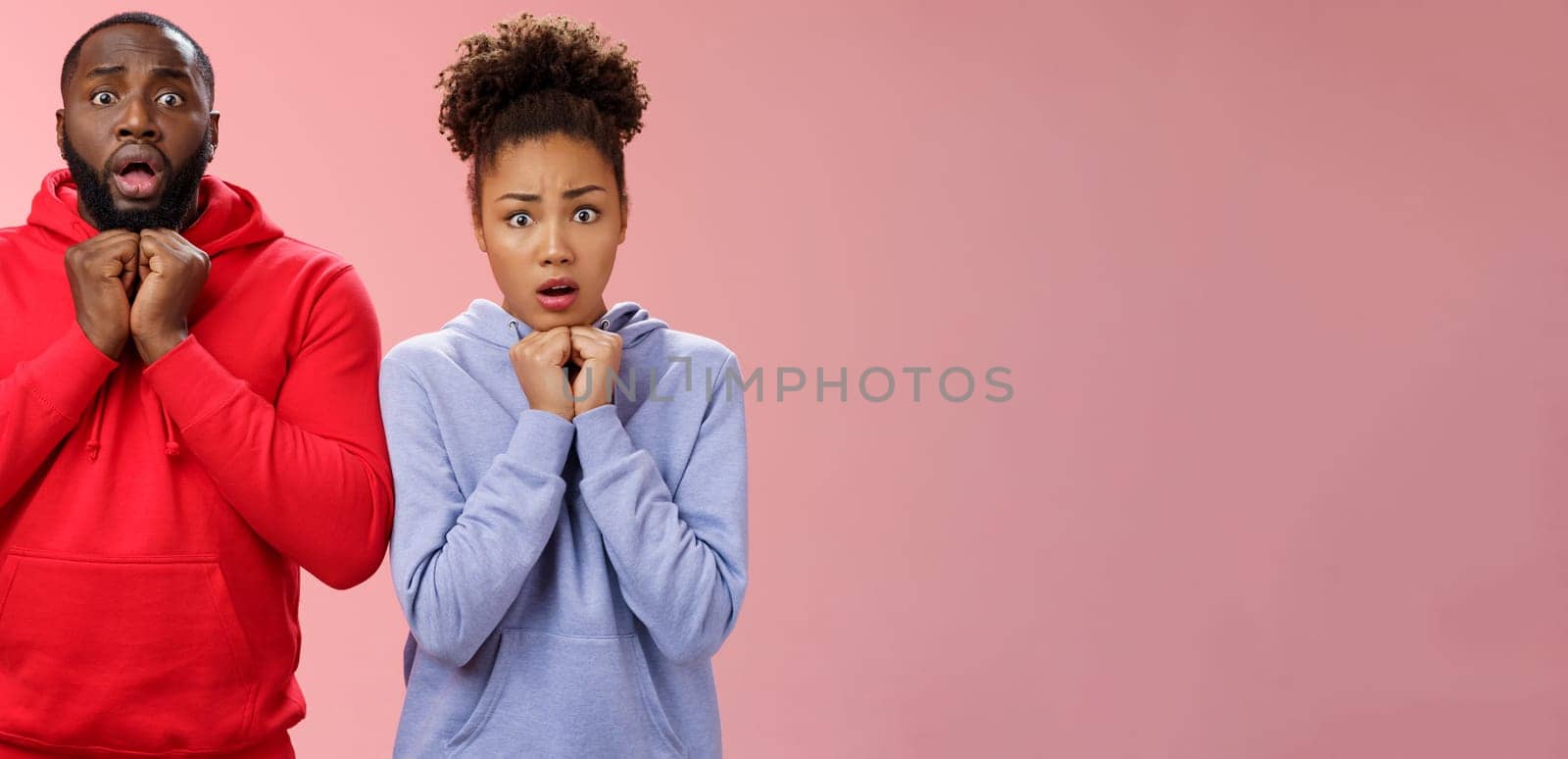 Upset worried two siblings watching together scary disturbing horror movie gasping frowning cringing shock intense emotions press hands chest widen eyes terrified standing nervous pink background by Benzoix