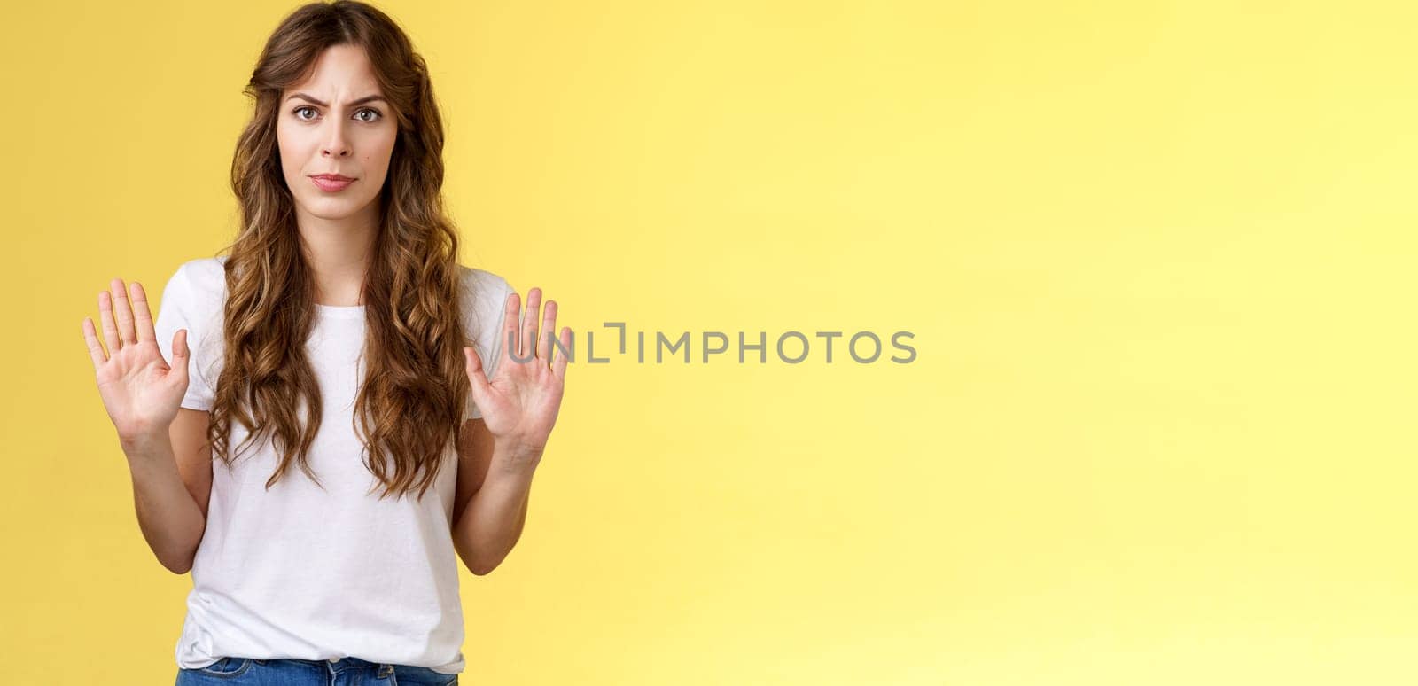 No thats enough. Serious-looking confident woman restrain man demand stay away give refusal look intense prohibit rejecting suspicious unpleasant offer stand yellow background. Copy space