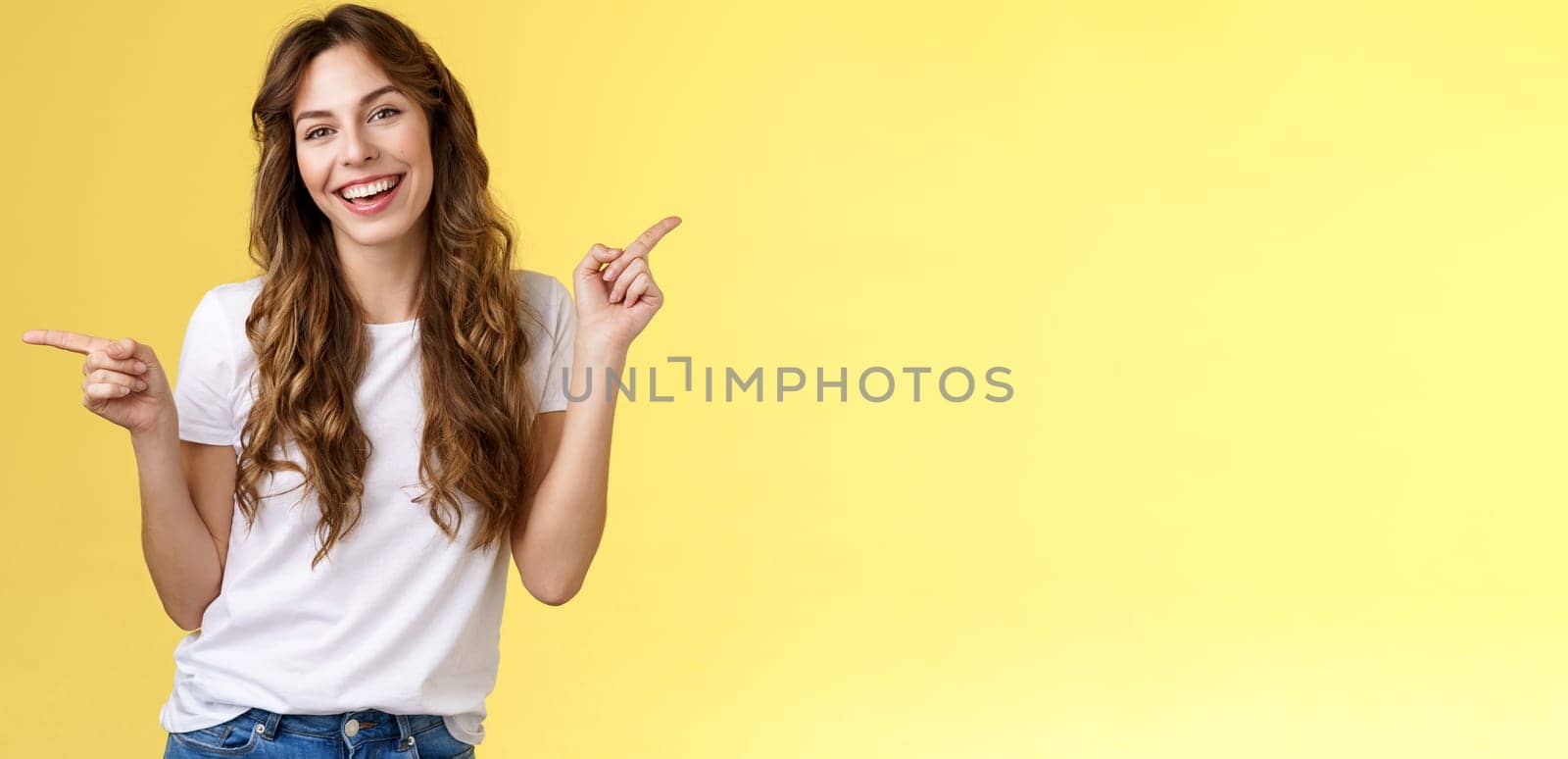 Girl have two suggestions pointing sideways. Cheerful charismatic curly-haired attractive woman pointing left right index fingers introduce promo products smiling broadly lively recommend ad by Benzoix