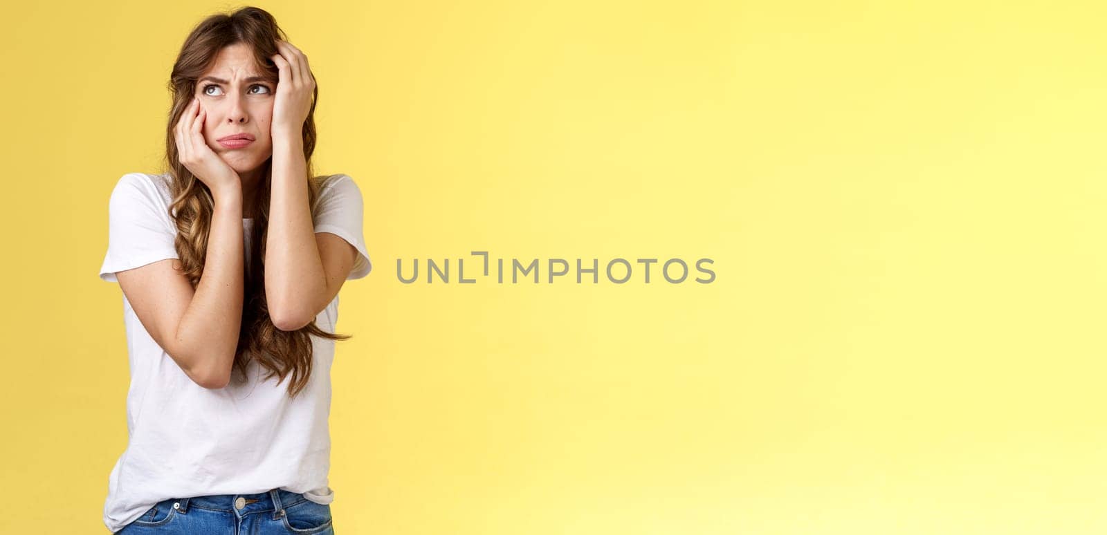 Shocked timid insecure young panicking woman wanna cry standing anxious frightened grab head both hands freak out look away praying for help terrified stand yellow background horrified. Lifestyle.