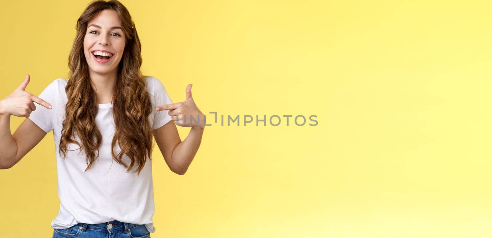 Haha awesome. Positive sincere attractive young woman curly long hair laughing joyfully pointing fingers center copy space white t-shirt chuckling having fun discuss great link show you promo.