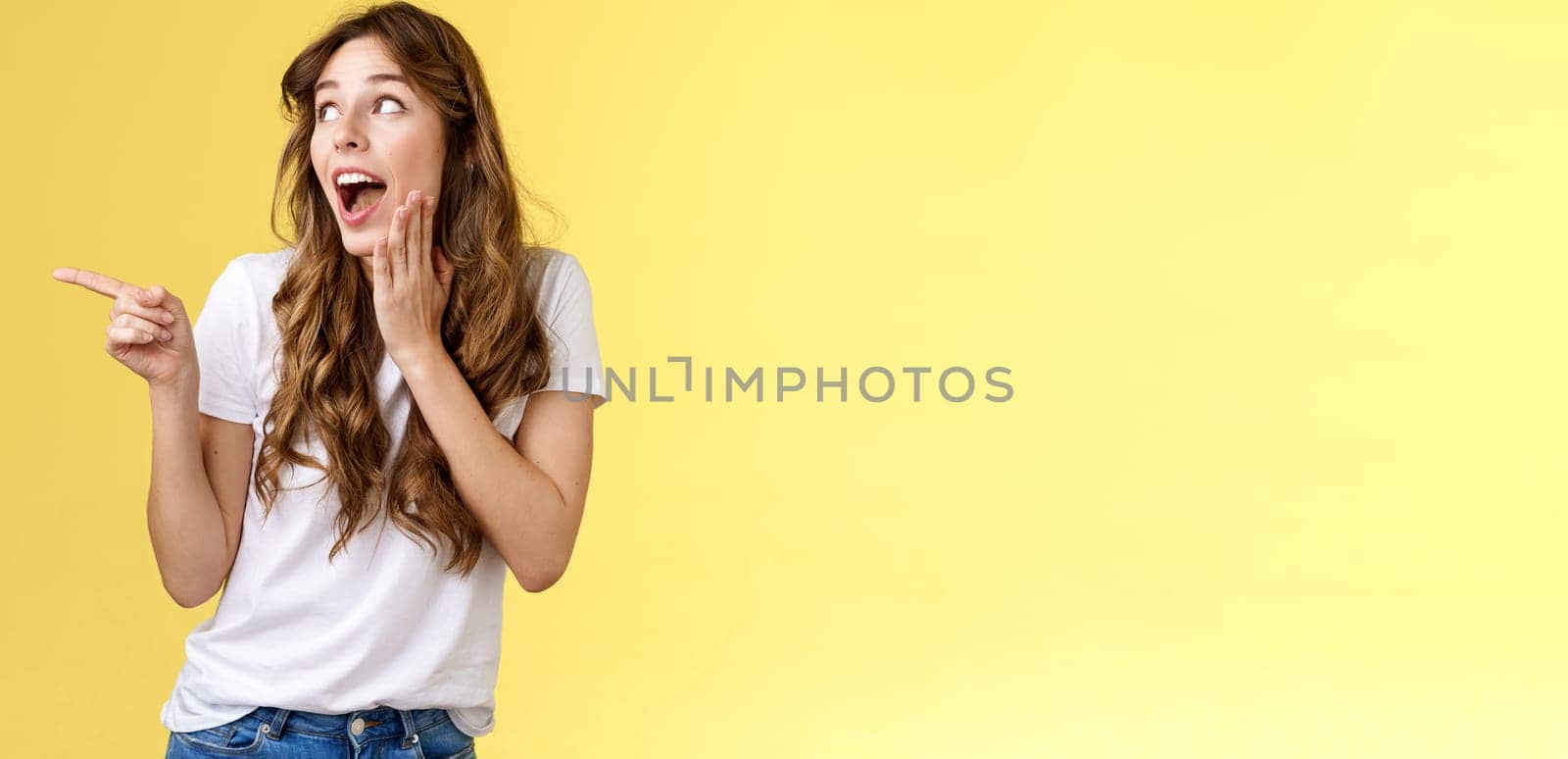 Silly flirty young attractive woman sighing admiration excitement checking out amazing stunning promo drop jaw smiling touch cheek touched delighted turn pointing left amused yellow background by Benzoix