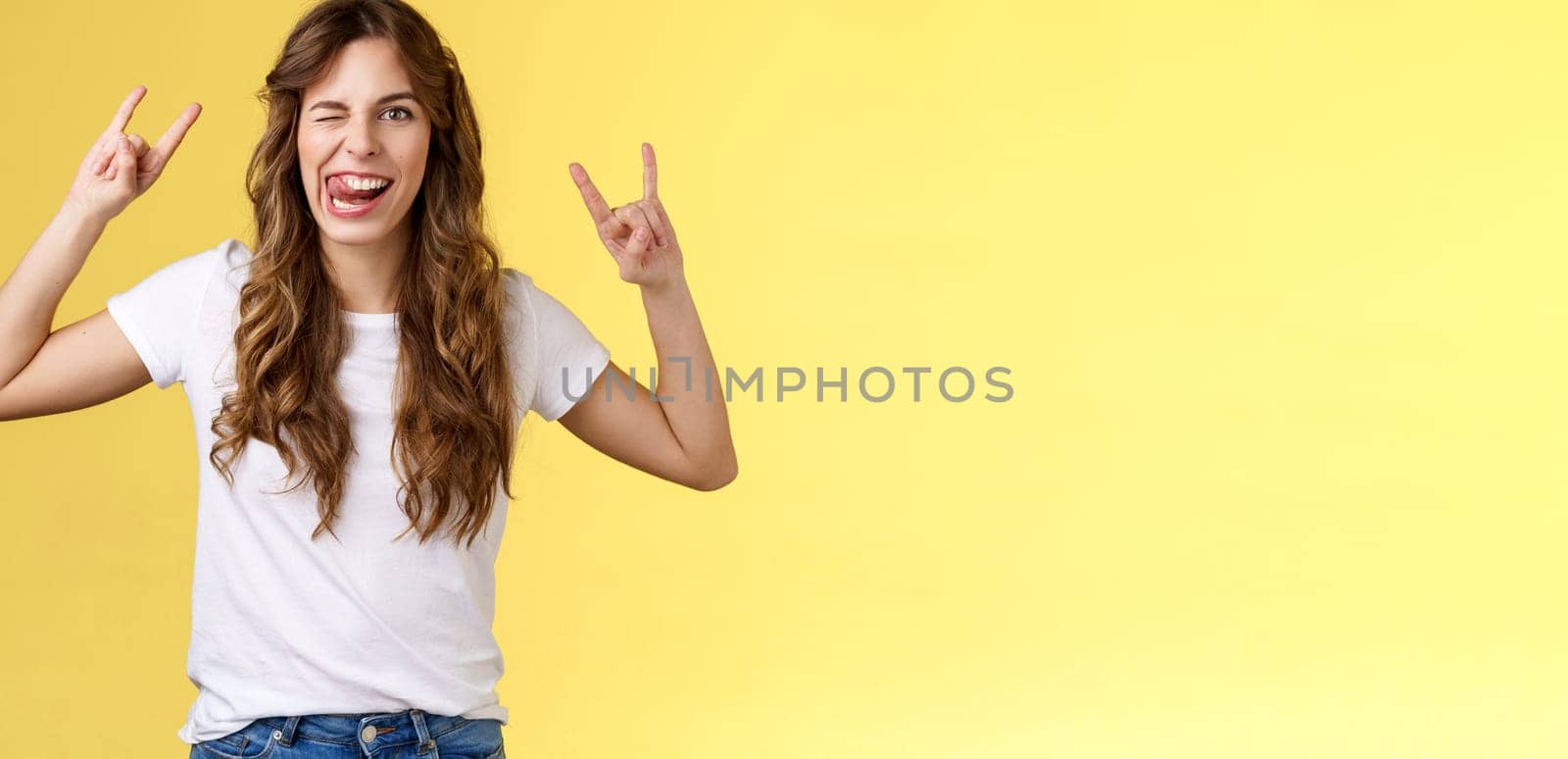 Awesome party having fun. Daring attractive carefree girl enjoy excellent event show rock-n-roll heavy metal gesture mimicking funny expressions wink stick tongue stand yellow background amused.