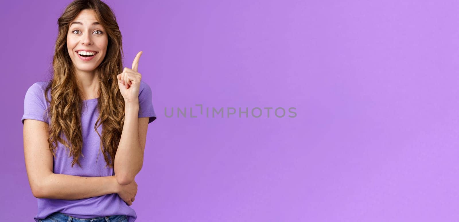 Got excellent idea. Attractive cheerful curly-haired female raise index finger eureka gesture smiling broadly made decision think up good plan share thought grinning ambushed purple background.