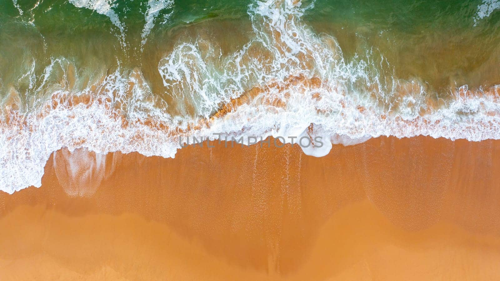Top view of waves crushing on sandy beach. Atlantic ocean beach aerial view