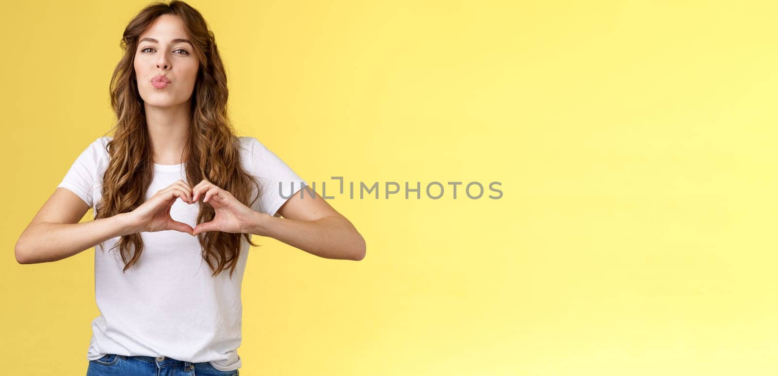 Passionate sensual attractive girlfriend express love sympathy show heart sign near chest folding lips kiss sending muah camera look admiration confess deep romantic feelings adore you by Benzoix