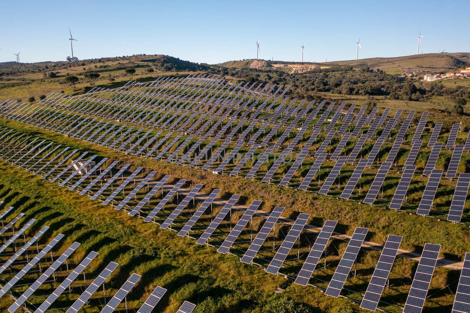 Long rows of photovoltaic panels at solar farm for converting energy of sun to electricity in concept of renewable energy and natural resources. Aerial view