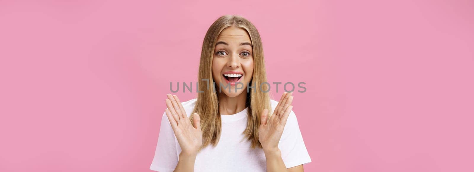 Woman learning awesome great news clasping hands in joy and excitement rejoicing feeling hapyp for friend smiling broadly and looking cheerful at camera with amused expression over pink background by Benzoix