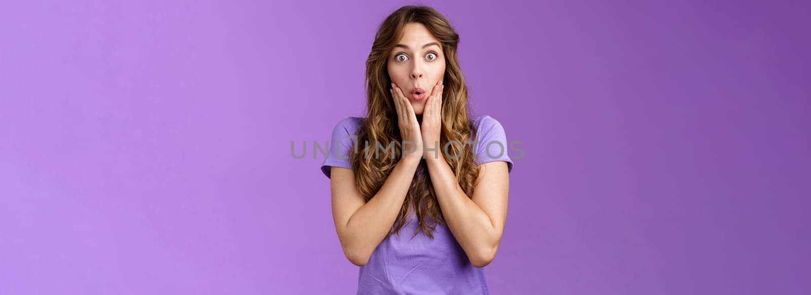 Impressed surprised attractive enthusiastic girlfriend hear shocking impressive rumor gasping fold lips wow gossiping touch cheeks ambushed stand purple background curious. Copy space