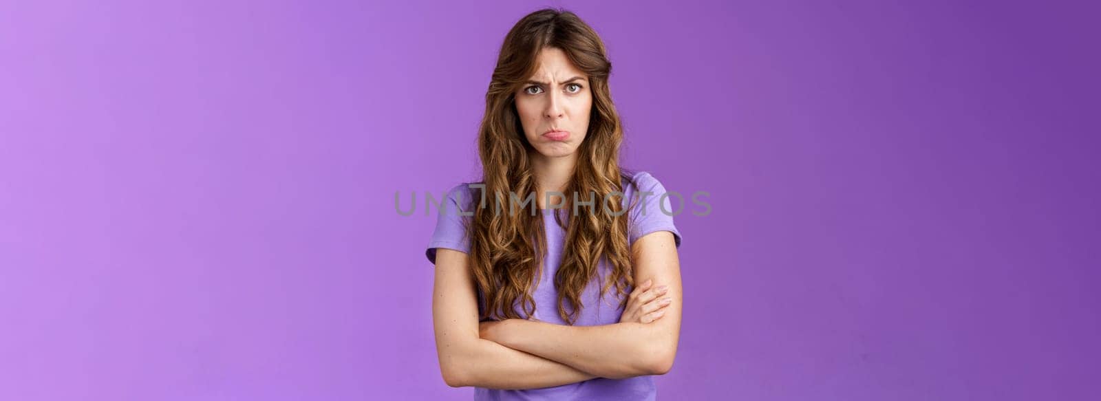 Offended silly timid cute girl sulking pouting lips frowning whining upset cross hands block pose insulted look moody camera disagree acting childish complaining unfair game purple background. Lifestyle.