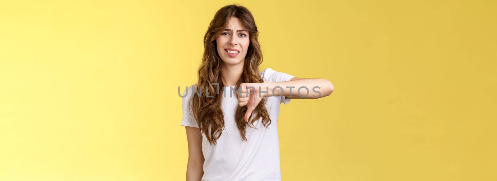 So lame you loser. Ignorant snobbish good-looking woman give own judgement negative opinion disagree grimacing cringe dislike show thumb down disappointed unimpressed yellow background.