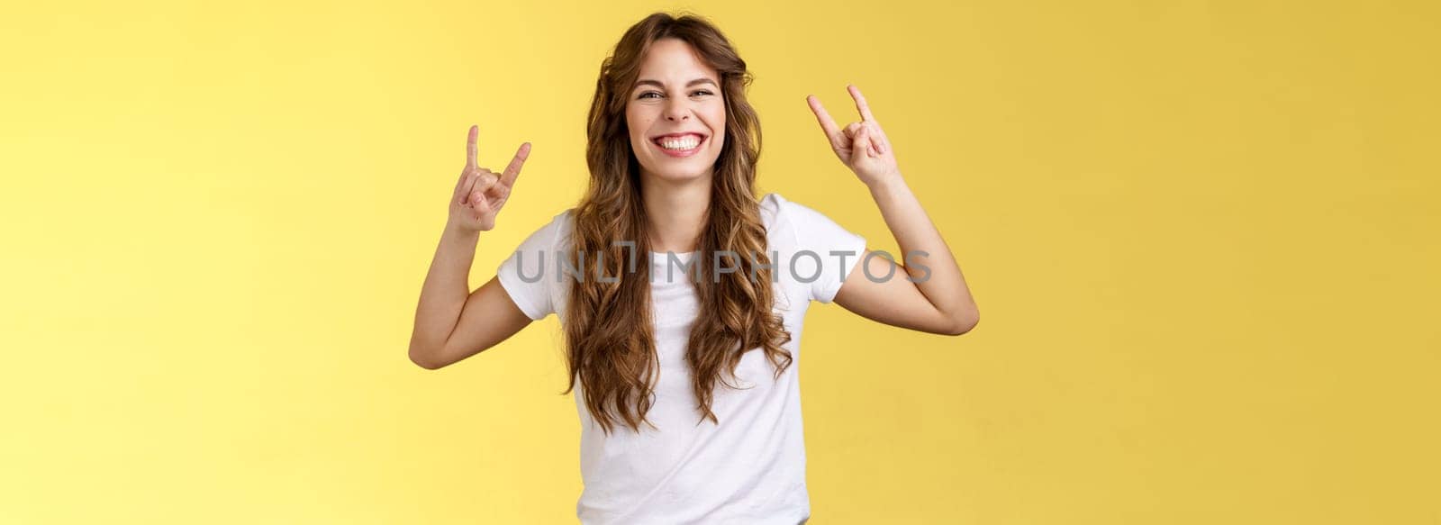 Enthusiastic charismatic lucky girl having fun enjoy awesome music show rock-n-roll gesture grinning thrilled like heavy-metal dancing upbeat positive standing entertained yellow background. Lifestyle.