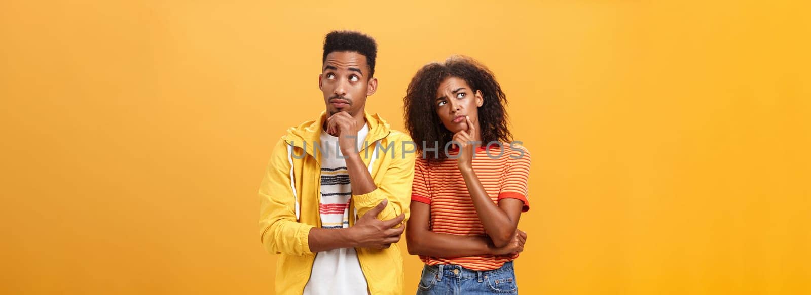 Two brains better than one. Thoughtful couple of african american friends in stylish urban outfit standing in thinker pose looking up determined and focused making up plan how spend evening. Relationship concept