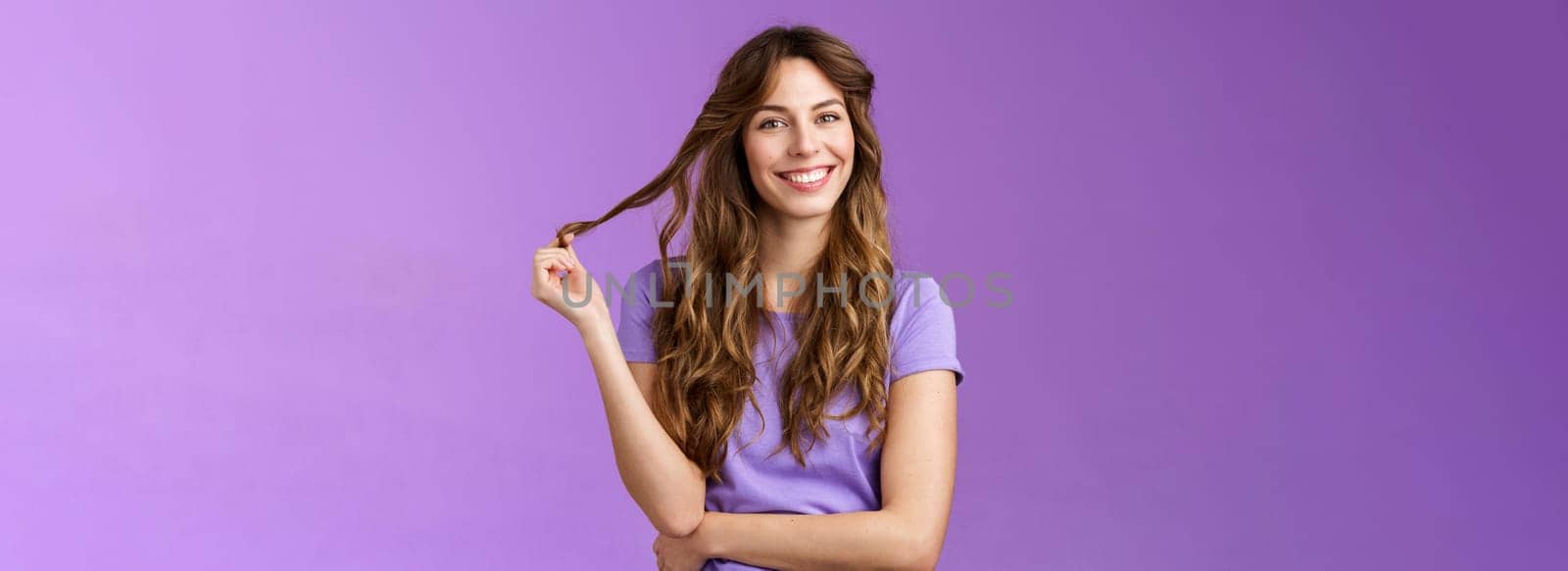 Tender confident good-looking outgoing curly-haired girl playing curl touch strand hair smiling enthusiastic hairstylist prepare good look evening date tilt head joyfully grinning cross arm chest. Lifestyle.