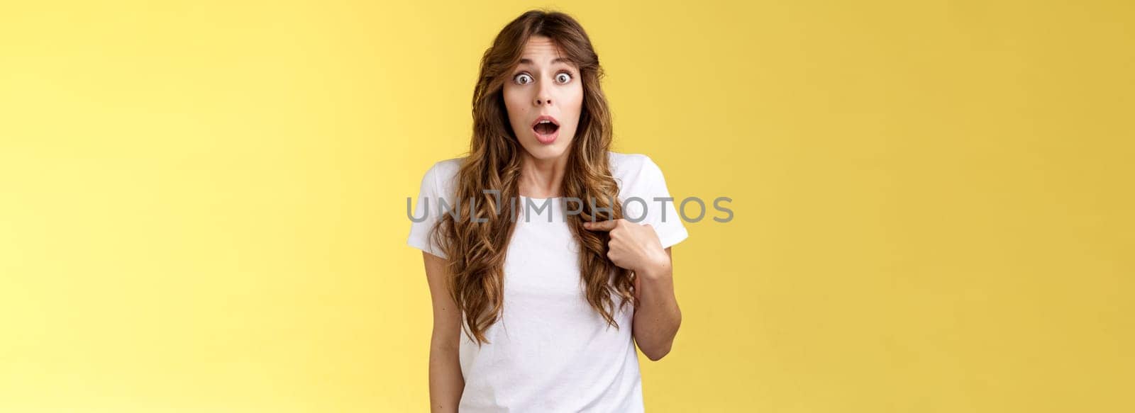 You mean me. Surprised questioned impressed gasping cute girl pointing herself indicating chest open mouth ambushed being picked chosen asking if person talking her stand yellow background.