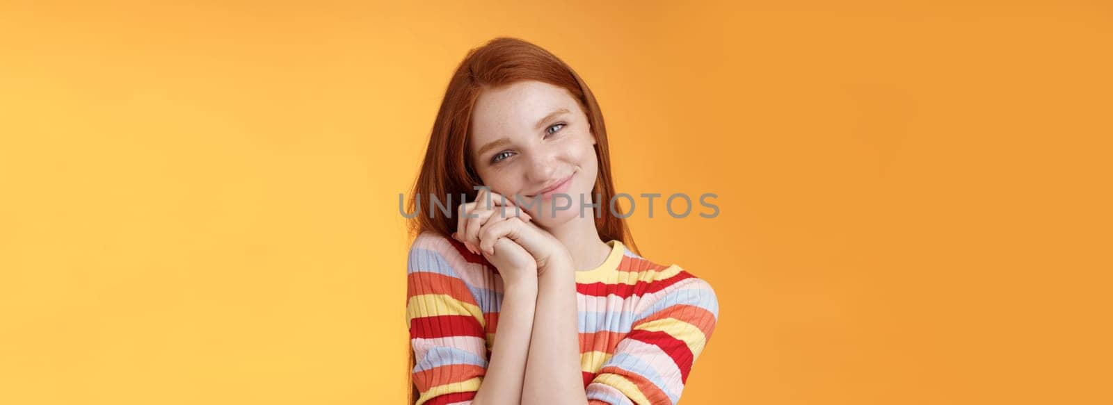 Sweet silly tender redhead young girl leaning palms touched smiling receive charming lovely gift standing thankful look affection sympathy accept dearest romantic gesture, orange background.