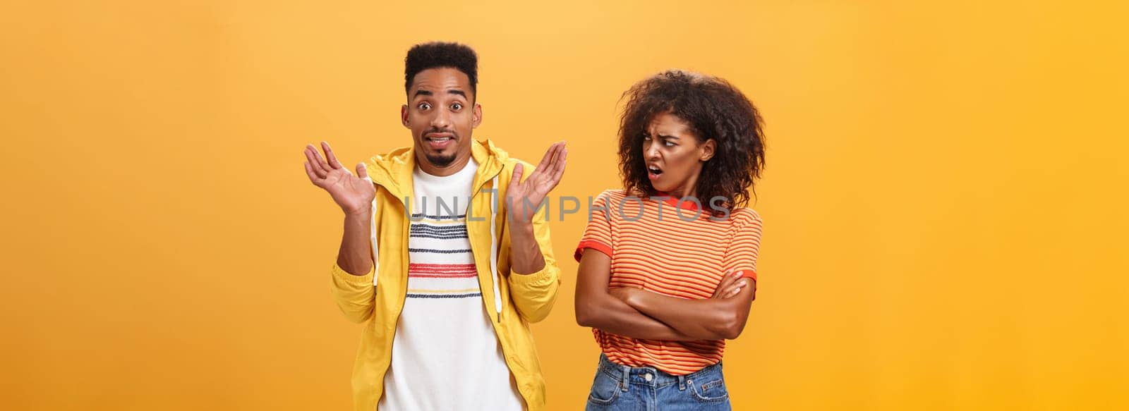 Jeez man what your problem. Offended displeased african american stylish and attractive girlfriend looking at boyfriend acting cool pretending he uninvolved shrugging with sorry look and smiling. Emotions and relationship concept