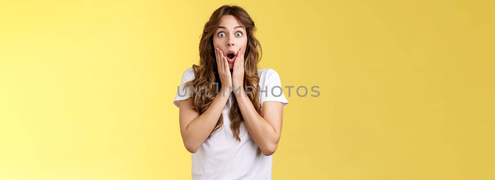 Shocked speechless impressed curly-haired silly girl drop jaw gasping astonished grab cheeks stare camera interested surprised checking out incredible unexpected scene yellow background by Benzoix