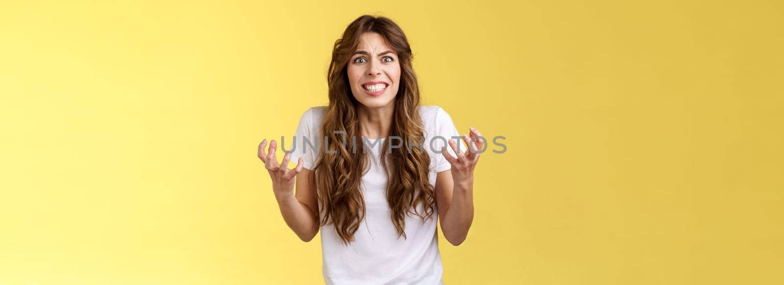 Annoyed curly-haired caucasian irritated distressed girl cringe outraged clench teeth frowning furious sqeez fists hateful complaining arguing pressured upset fighting have quarrel yellow background by Benzoix