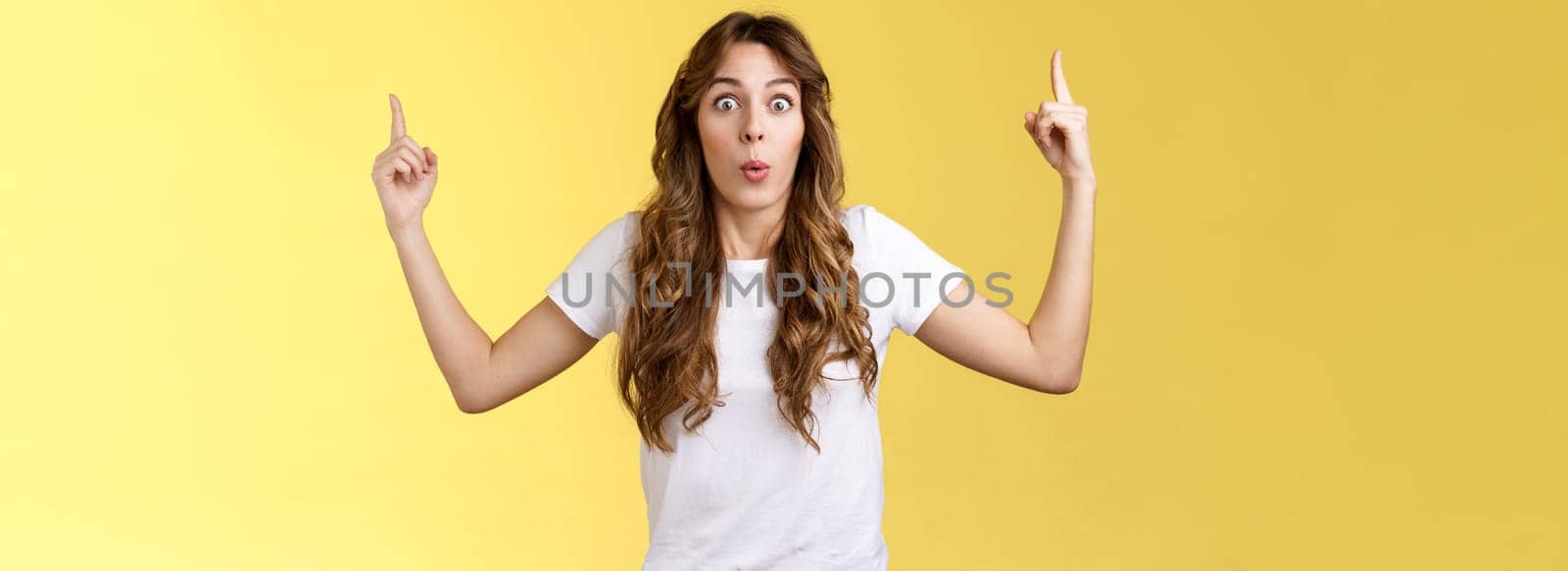 Omg stunning promo look. Surprised astonished impressed good-looking girl stare camera excited react awesome promo raise index fingers pointing up telling you about incredible advertisement.