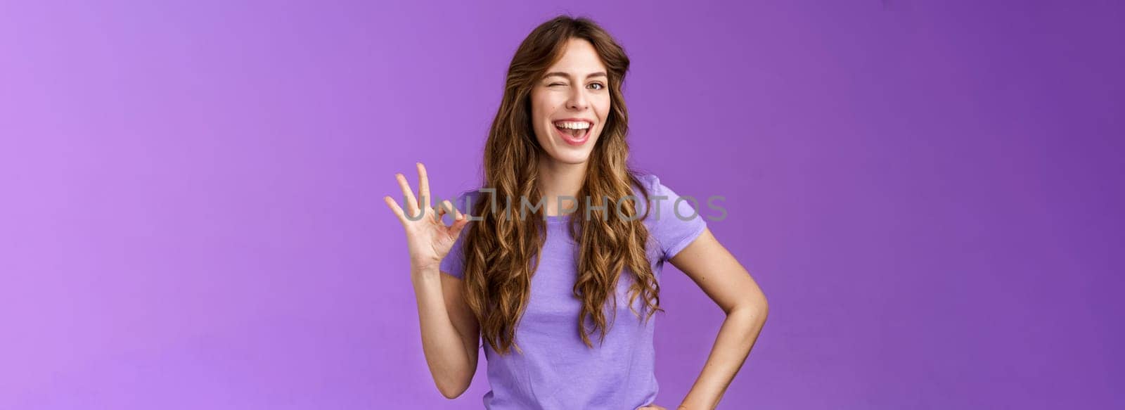 Okay got it. Cheeky flirty girlfriend winking coquettish show alright okay ok sign smiling broadly reassure friend outfit awesome express approval agree good idea stand purple background pleased by Benzoix