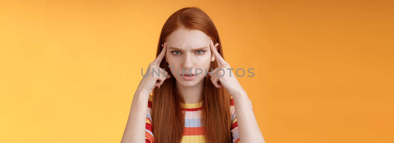 Puzzled serious-looking stressed-out young tired female student frowning look unhappy touching temples thinking trying focus, concentrate attention lecture memorizing hometask, orange background by Benzoix
