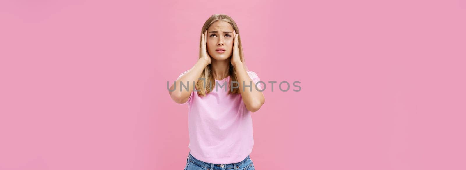 Woman trying recall important number touching temples with hands looking up concerned and focused having trouble to remember information standing intense against pink background. Body language and emotions concept