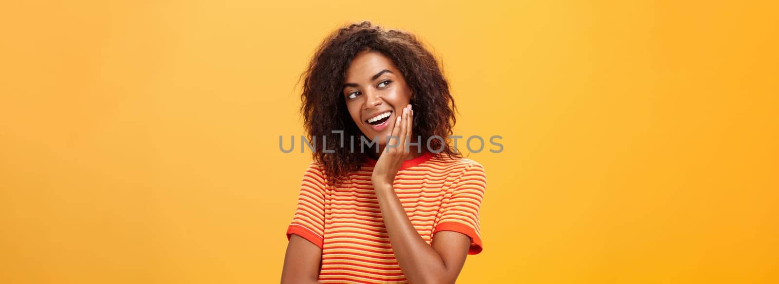 Cute creative and feminine stylish african american young female in striped t-shirt leaning head on palm gazing left with curious and adorable expression delightfully listening interesting story. Lifestyle.