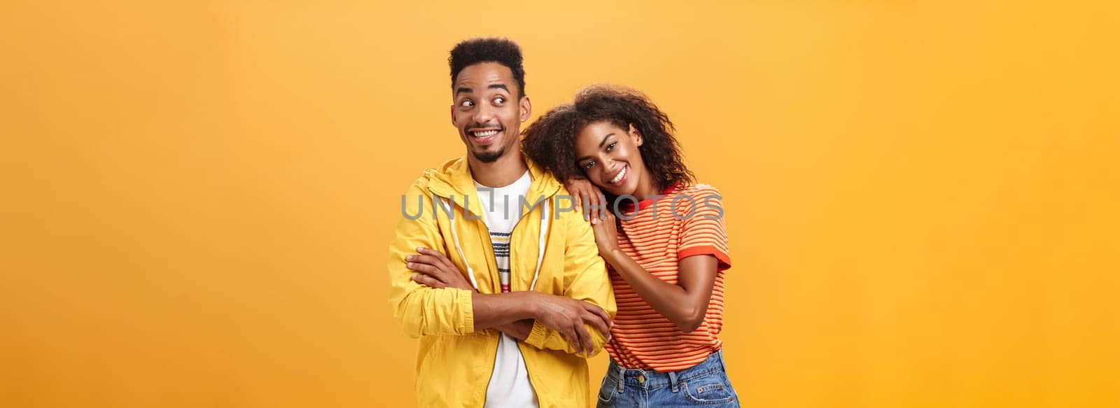 Guy feeling happy girl lean on his shoulder grinning and chuckling from happiness standing pleased and joyful over orange background while woman hugging best friend upbeat she can rely on him. Relationship concept