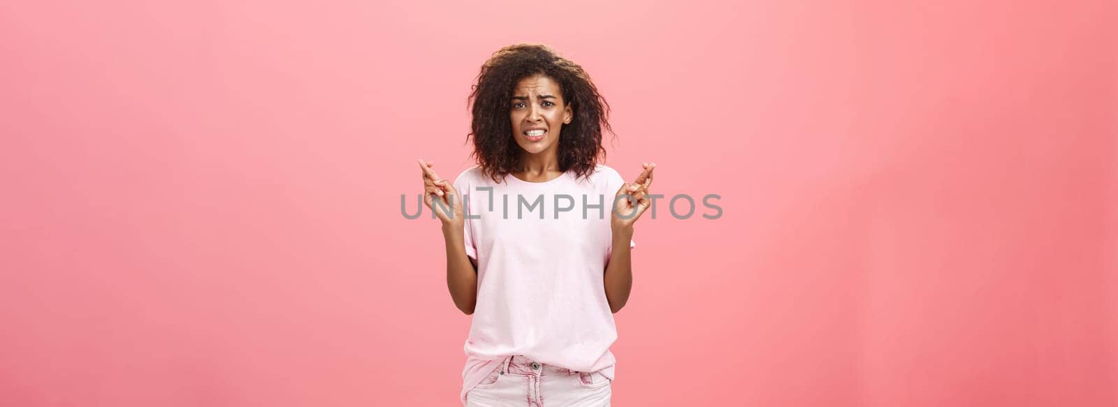 Hope she gets positive result. Portrait of worried intense hopeful good-looking young african american female coworker frowning clenching teeth and crossing fingers for good luck while making wish. Copy space